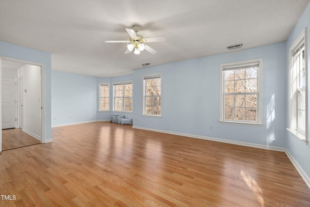 interior space with visible vents, light wood-style flooring, baseboards, and a textured ceiling