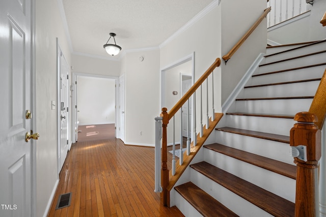 entryway with baseboards, visible vents, ornamental molding, hardwood / wood-style floors, and stairs