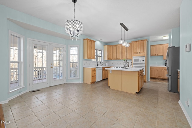 kitchen featuring white appliances, light countertops, a center island with sink, and light tile patterned flooring