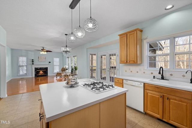 kitchen featuring light tile patterned floors, light countertops, a premium fireplace, a sink, and white appliances