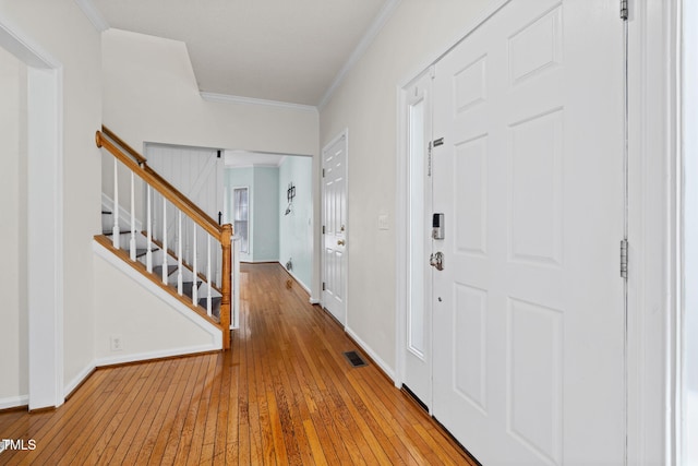 entrance foyer with visible vents, baseboards, stairway, wood-type flooring, and crown molding