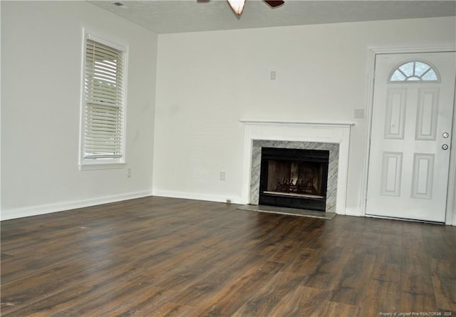 unfurnished living room featuring baseboards, a premium fireplace, a ceiling fan, and wood finished floors