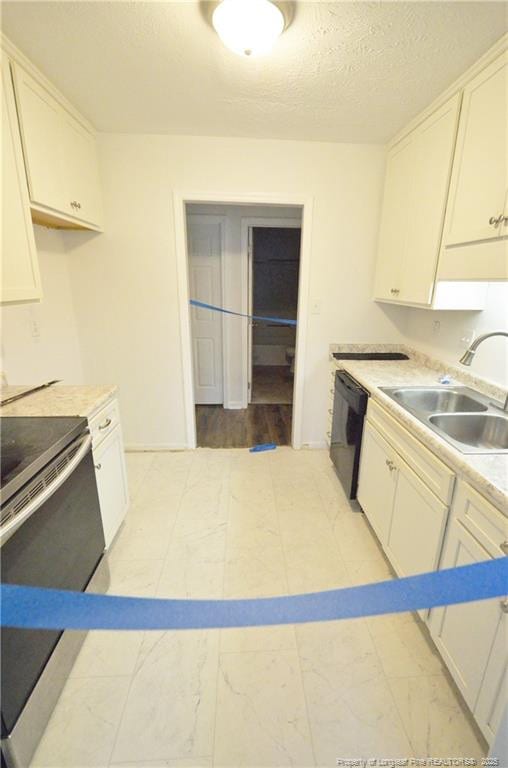 kitchen featuring black dishwasher, white cabinets, a sink, and stainless steel range with electric cooktop