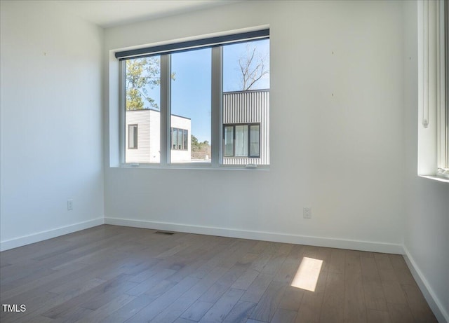 empty room with visible vents, baseboards, and wood finished floors