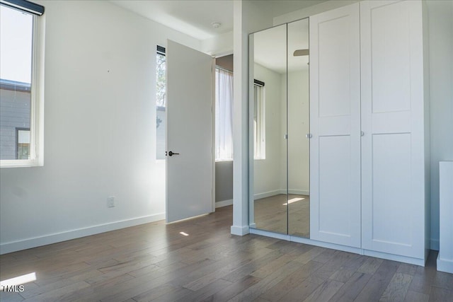 unfurnished bedroom with a closet, baseboards, and wood finished floors