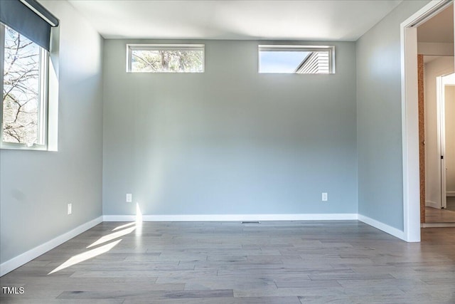 spare room with baseboards and wood finished floors