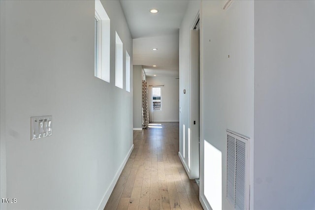 hallway with recessed lighting, visible vents, baseboards, and hardwood / wood-style flooring