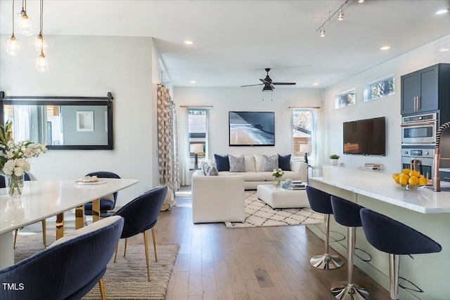 living area with a ceiling fan, recessed lighting, rail lighting, and hardwood / wood-style flooring