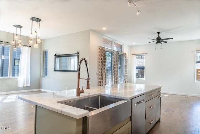 kitchen featuring a healthy amount of sunlight, stainless steel dishwasher, a sink, and wood finished floors