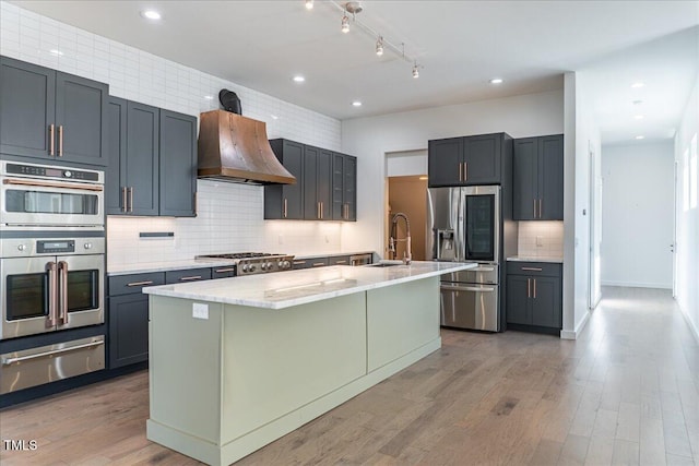 kitchen featuring extractor fan, stainless steel appliances, a sink, light wood-type flooring, and a warming drawer