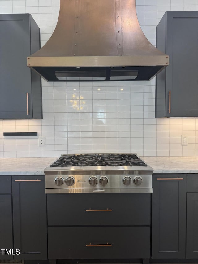 kitchen with light stone countertops, stainless steel gas stovetop, island range hood, and decorative backsplash