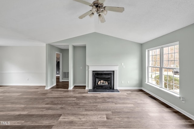 unfurnished living room featuring a fireplace with raised hearth, wood finished floors, visible vents, and baseboards