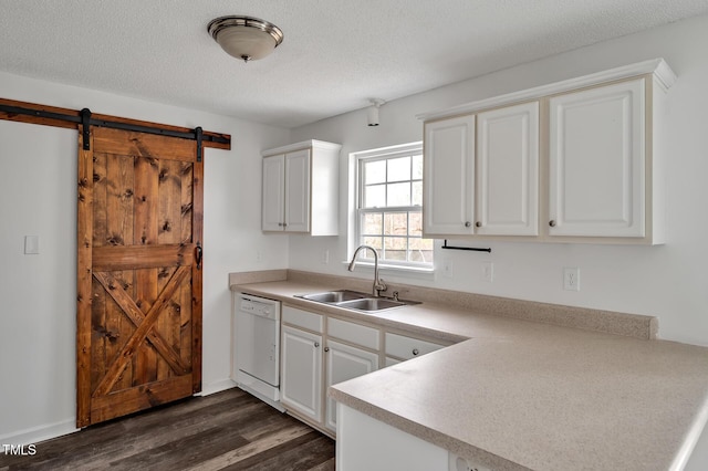 kitchen featuring a barn door, dishwasher, dark wood-type flooring, a textured ceiling, and a sink