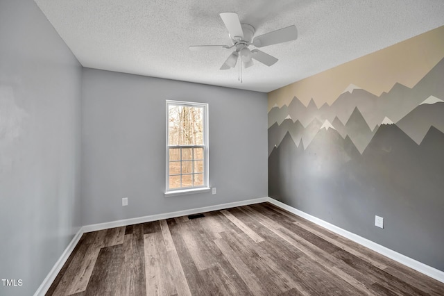 spare room with visible vents, baseboards, dark wood finished floors, and a textured ceiling