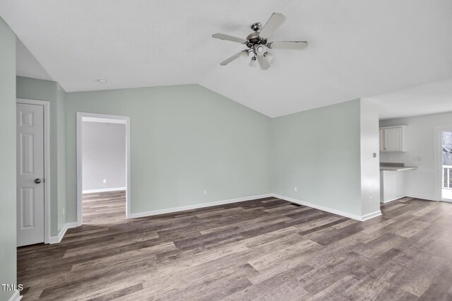 unfurnished living room with dark wood-type flooring, vaulted ceiling, baseboards, and ceiling fan