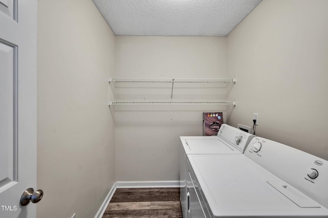 laundry room with dark wood-style floors, a textured ceiling, washer and dryer, laundry area, and baseboards