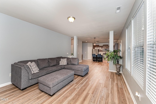 living area with light wood-type flooring, visible vents, and baseboards