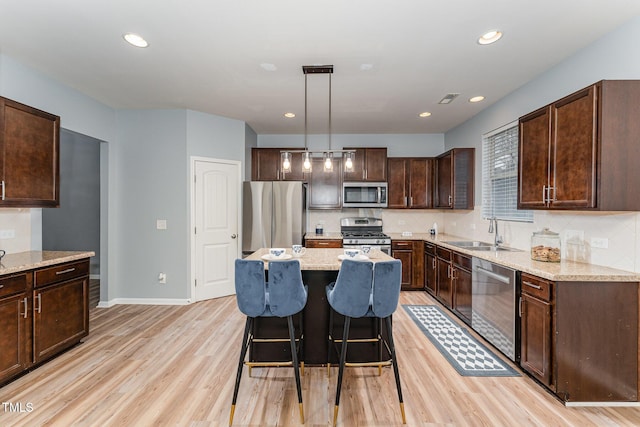 kitchen featuring appliances with stainless steel finishes, light wood-style floors, a sink, and dark brown cabinetry