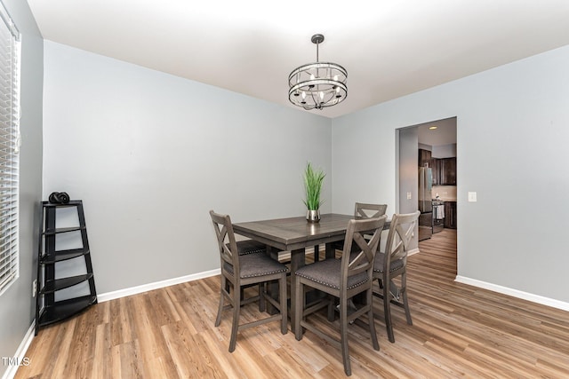 dining area with an inviting chandelier, baseboards, and light wood finished floors