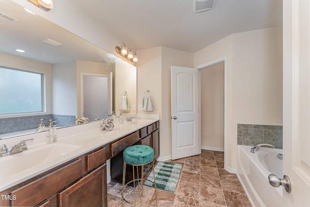 bathroom featuring visible vents, a sink, a garden tub, and double vanity