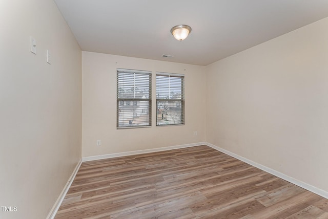 unfurnished room with light wood-style flooring, visible vents, and baseboards