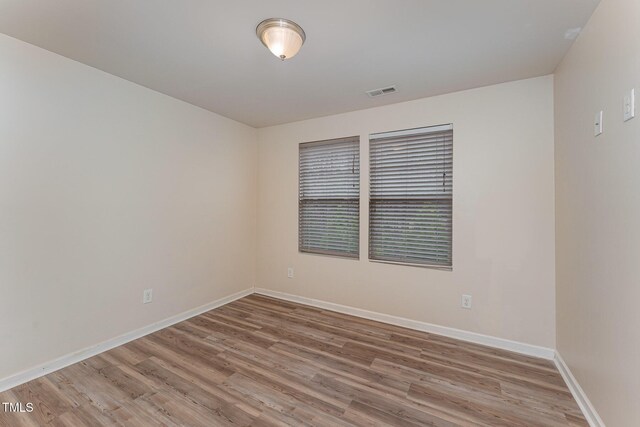 spare room featuring light wood-type flooring, baseboards, and visible vents