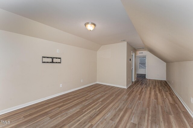 bonus room with vaulted ceiling, light wood-style flooring, and baseboards