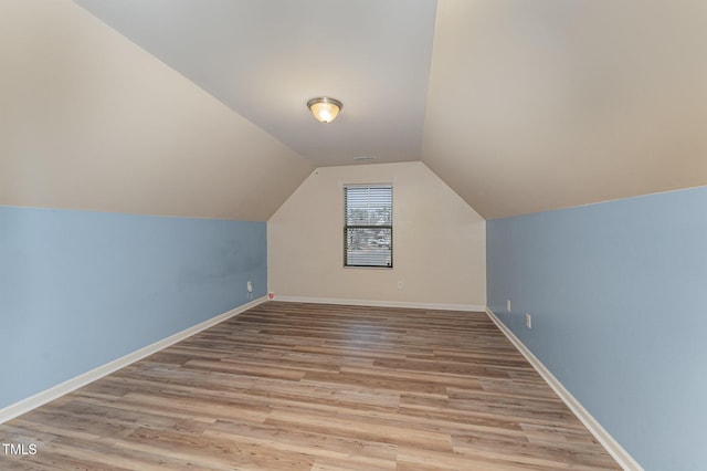 additional living space with visible vents, vaulted ceiling, baseboards, and wood finished floors