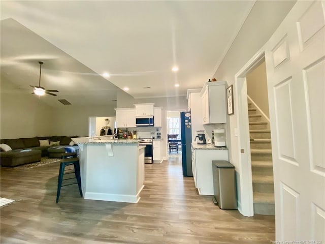 kitchen with light wood-style floors, freestanding refrigerator, open floor plan, white cabinetry, and a kitchen breakfast bar