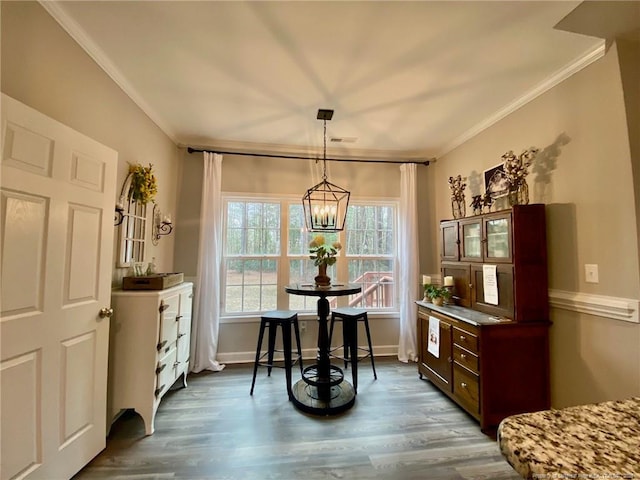 dining space featuring dark wood-style floors, baseboards, a chandelier, and crown molding