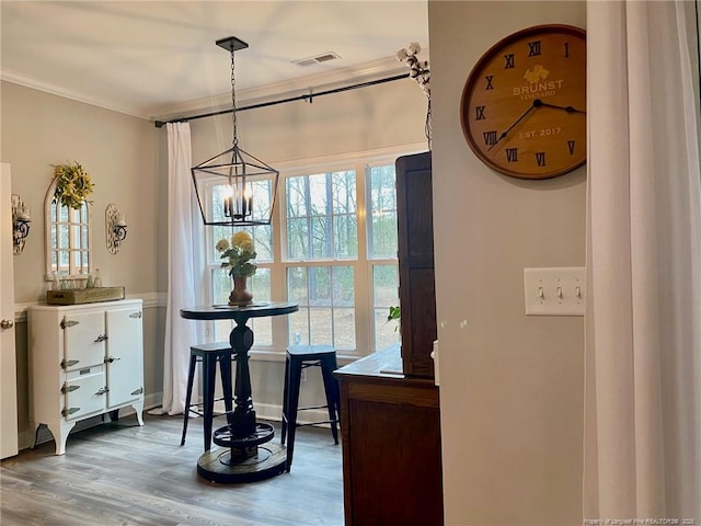 dining room with an inviting chandelier, wood finished floors, visible vents, and crown molding