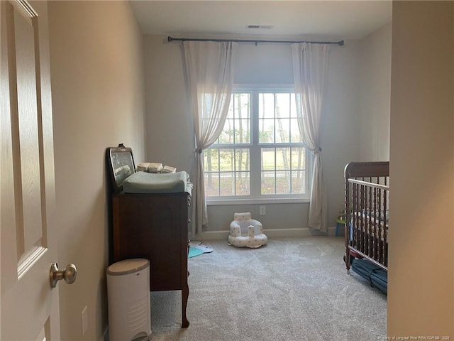 carpeted bedroom with a crib, visible vents, and baseboards