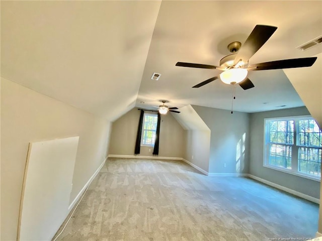 additional living space with light carpet, lofted ceiling, visible vents, and baseboards