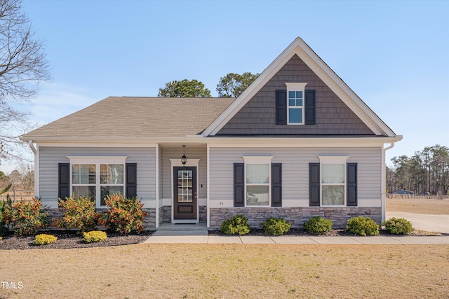 craftsman-style home featuring stone siding and a front yard