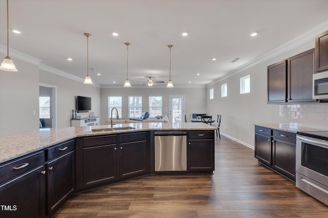 kitchen featuring a sink, open floor plan, ornamental molding, appliances with stainless steel finishes, and dark wood finished floors