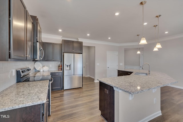 kitchen featuring appliances with stainless steel finishes, decorative backsplash, a sink, and wood finished floors