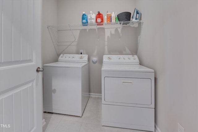 laundry room with laundry area, baseboards, washing machine and clothes dryer, and light tile patterned floors