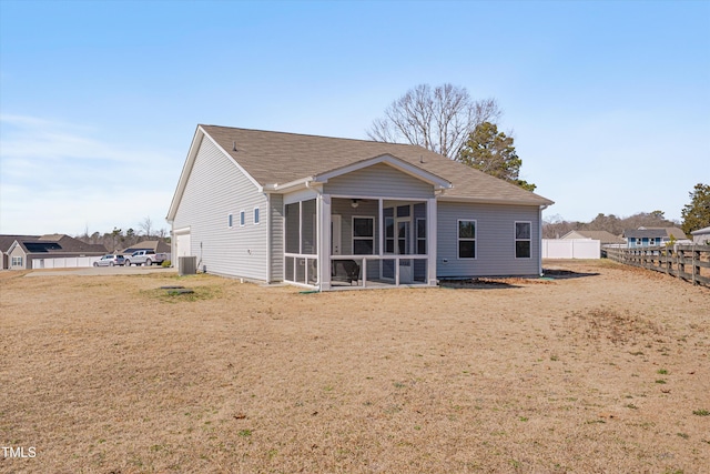 back of house featuring a yard, roof with shingles, fence, and a sunroom