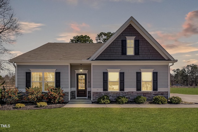 craftsman-style house featuring stone siding and a lawn