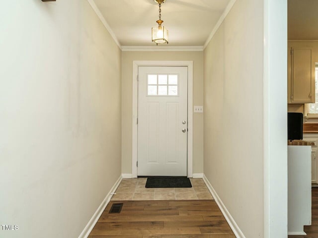 entryway featuring light wood finished floors, ornamental molding, visible vents, and baseboards