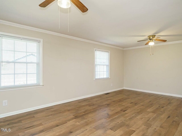 spare room with baseboards, ceiling fan, wood finished floors, and crown molding