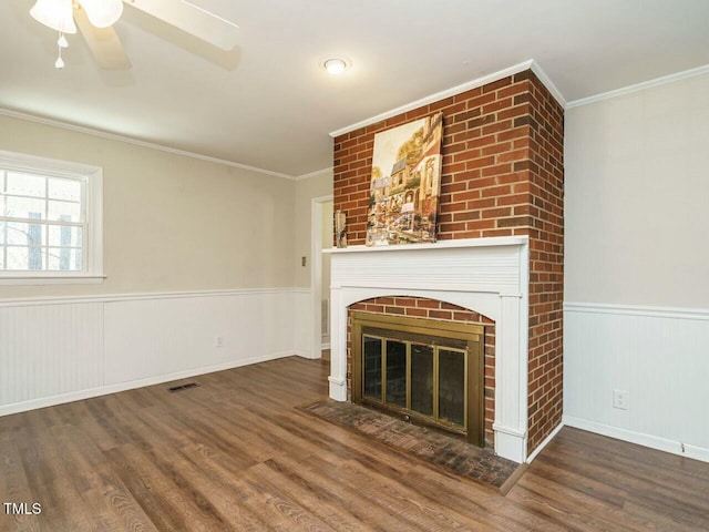 unfurnished living room with ornamental molding, wainscoting, visible vents, and wood finished floors