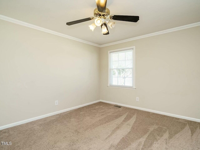 carpeted spare room featuring baseboards, ceiling fan, visible vents, and crown molding