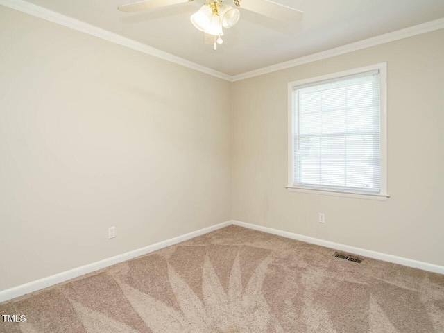 carpeted spare room with a ceiling fan, visible vents, crown molding, and baseboards