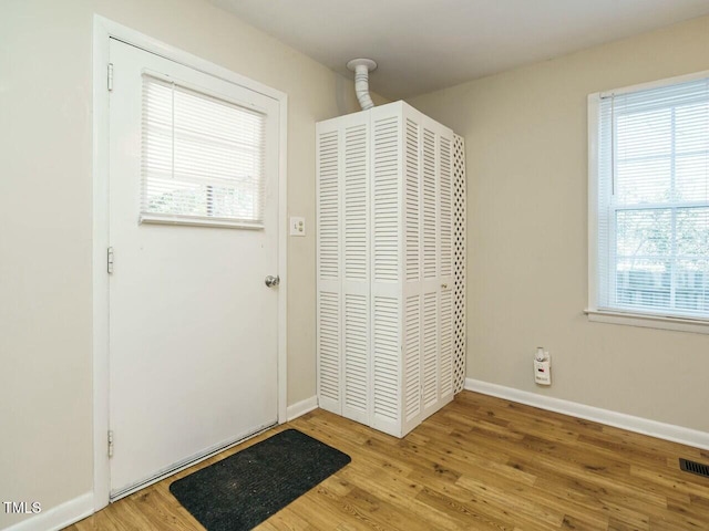 doorway featuring visible vents, baseboards, and wood finished floors