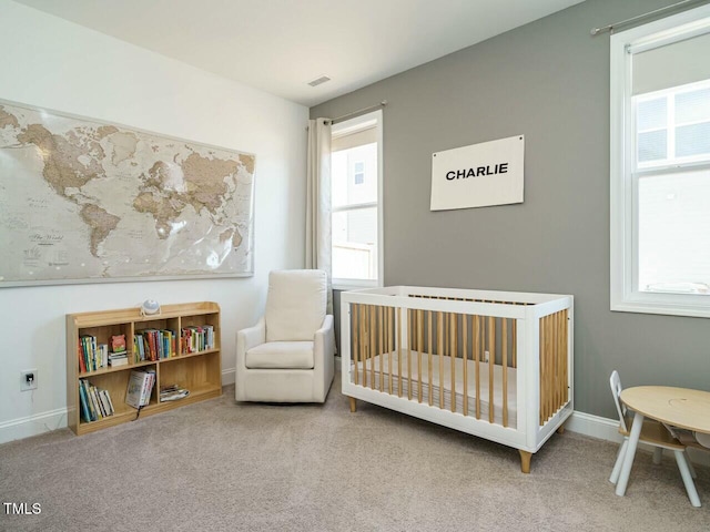 bedroom featuring a nursery area, multiple windows, baseboards, and carpet flooring