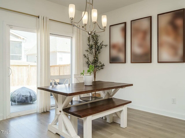 dining space with a chandelier, light wood-style flooring, and baseboards