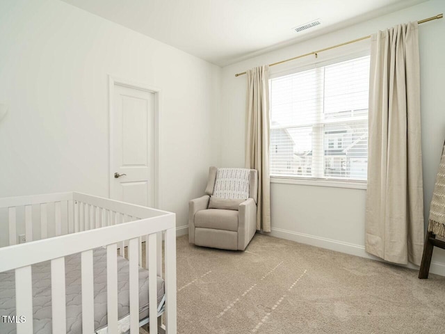 bedroom featuring baseboards, visible vents, a crib, and carpet flooring