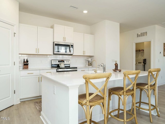 kitchen with visible vents, light wood-style floors, light countertops, appliances with stainless steel finishes, and tasteful backsplash