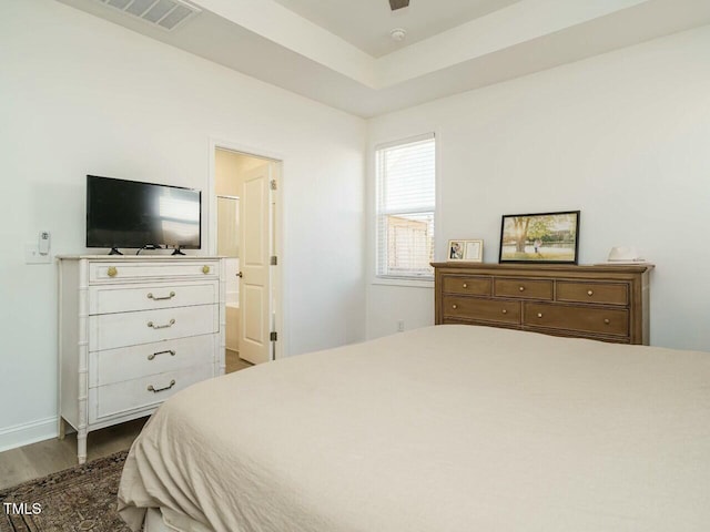 bedroom with baseboards, visible vents, a ceiling fan, dark wood-type flooring, and ensuite bathroom